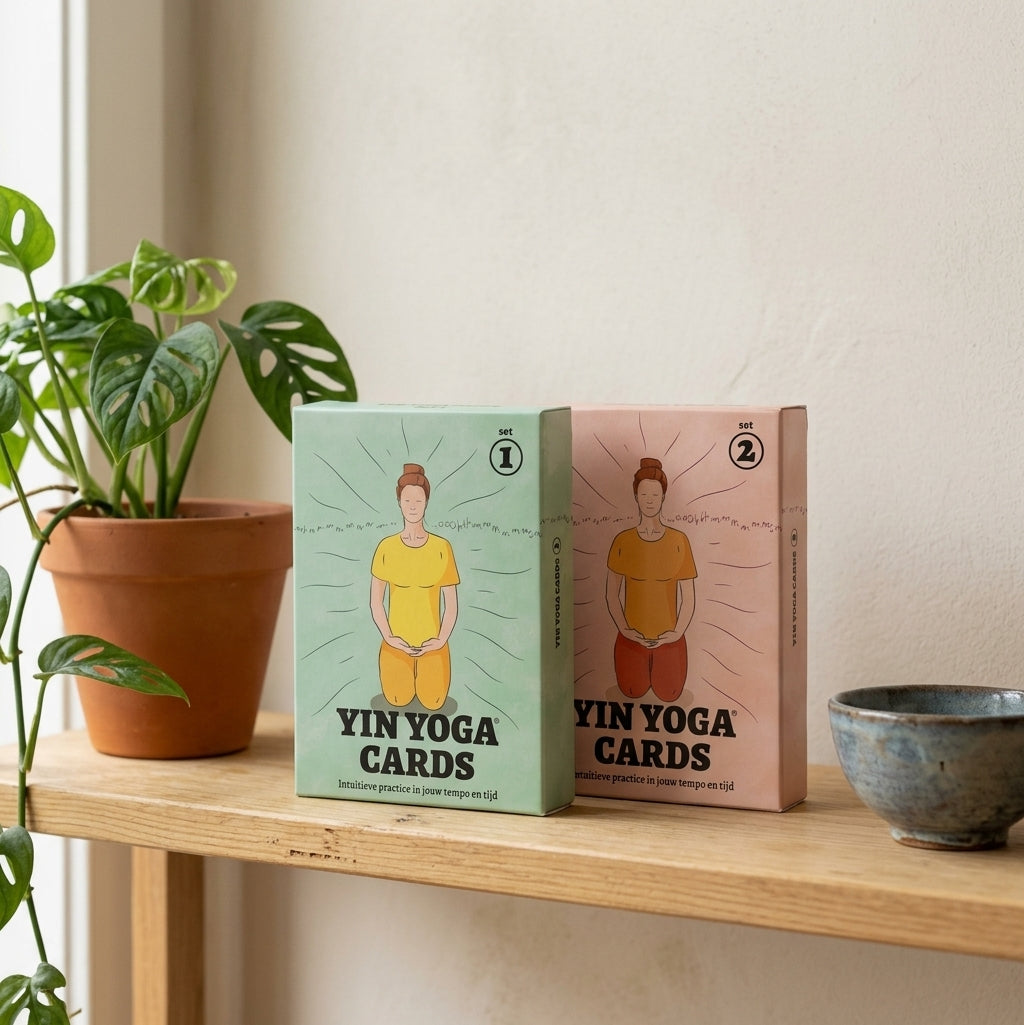 Yin Yoga Cards set 1 en set 2 op een houten plank naast een kamerplant en een keramieken kom