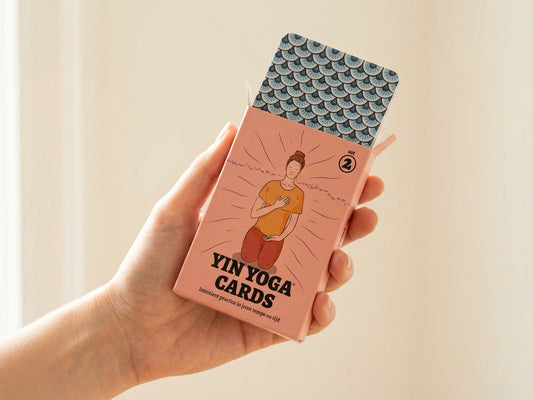 Hand houdt de roze doos van Yin Yoga Cards set 2 vast, met de kaarten half uit de doos